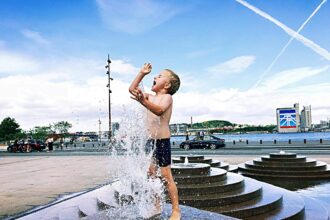 Un niño se refresca en una fuente